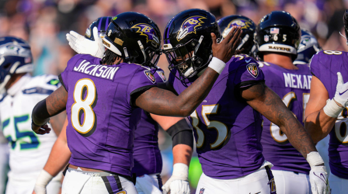 Lamar Jackson reaches out to tap Gus Edwards’s helmet in celebration